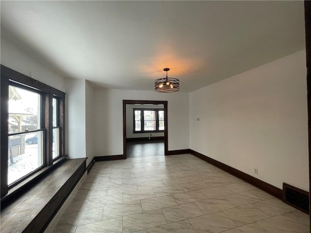 unfurnished room with a notable chandelier