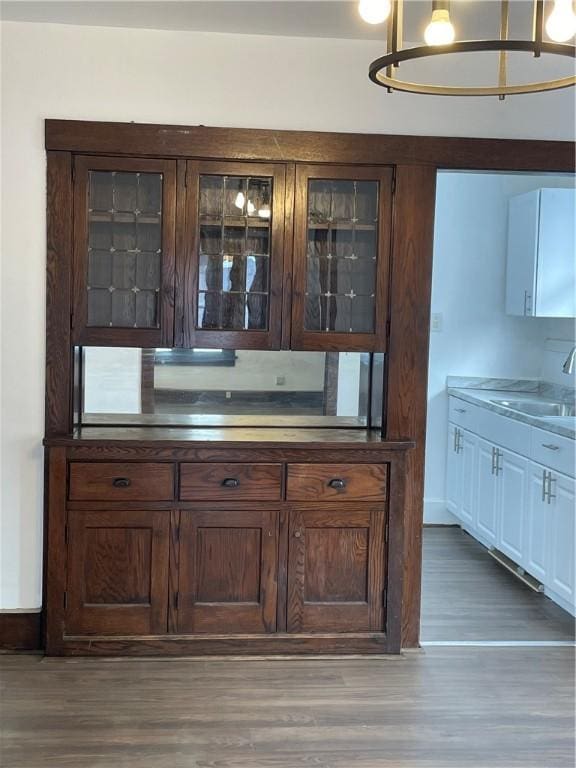 bar with sink, white cabinets, and dark hardwood / wood-style flooring