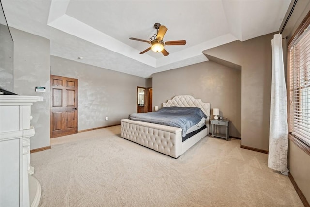 carpeted bedroom featuring ceiling fan and a raised ceiling