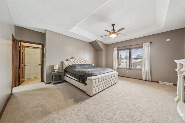 bedroom featuring ceiling fan, light carpet, and a tray ceiling