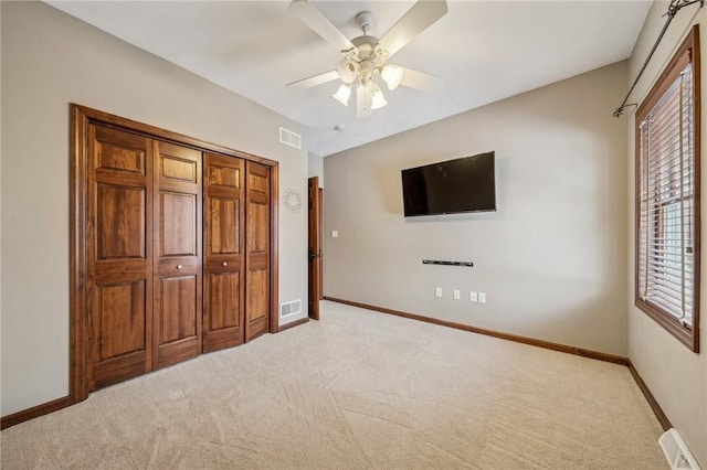 unfurnished bedroom with ceiling fan, light colored carpet, and a closet