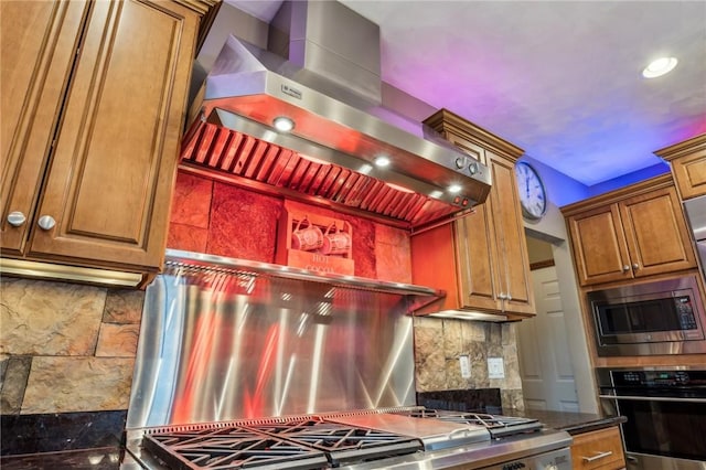 kitchen with backsplash, stainless steel appliances, dark stone counters, and range hood