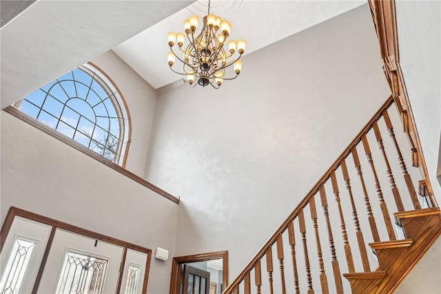 stairway featuring a high ceiling, a wealth of natural light, and an inviting chandelier