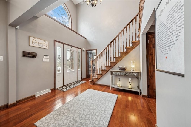 entryway featuring hardwood / wood-style flooring, a chandelier, and a towering ceiling