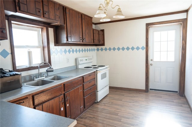 kitchen featuring sink, decorative light fixtures, light wood-type flooring, electric range, and an inviting chandelier