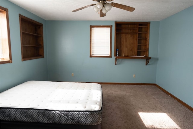 unfurnished bedroom featuring ceiling fan, carpet, and a textured ceiling