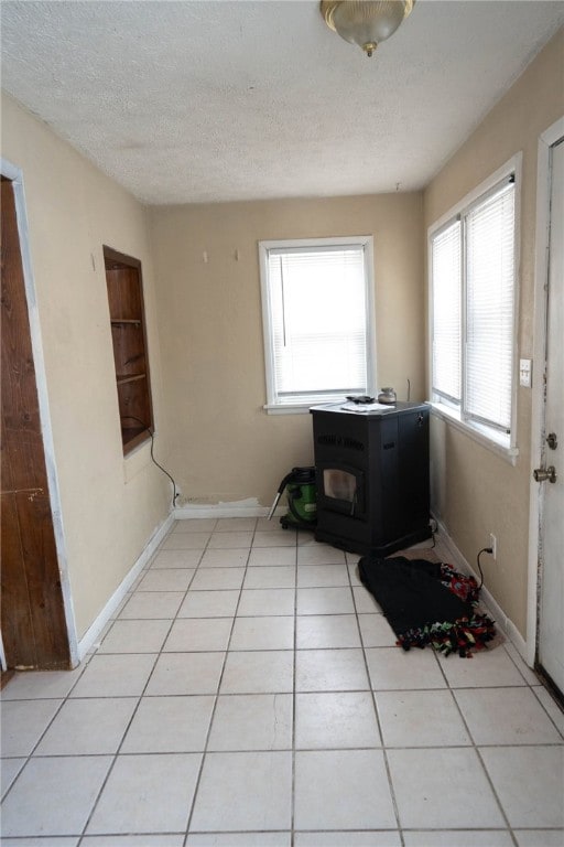 clothes washing area with light tile patterned flooring, a textured ceiling, and a wood stove