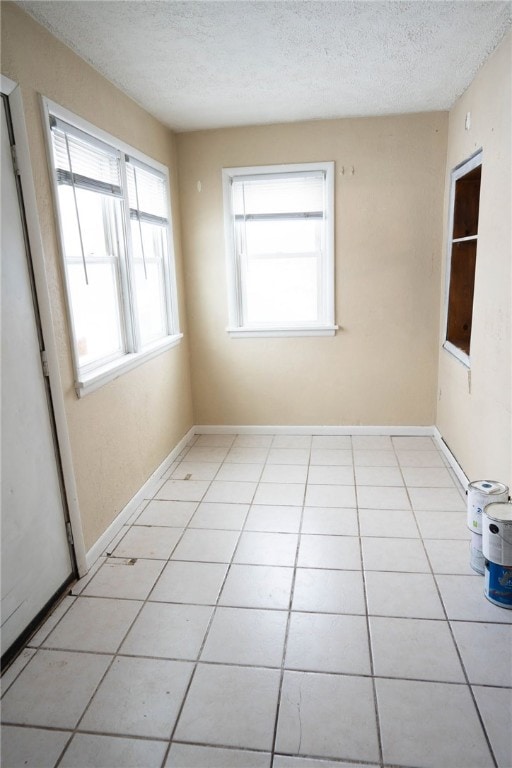 unfurnished room with a textured ceiling and light tile patterned floors