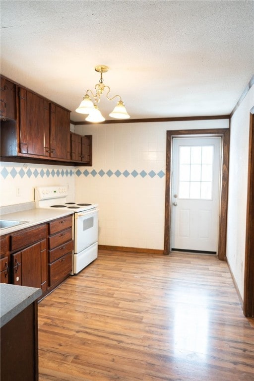 kitchen featuring light wood-type flooring, hanging light fixtures, electric range, a textured ceiling, and an inviting chandelier