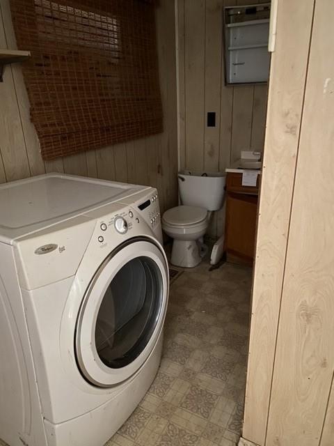 laundry room with wooden walls and washer / dryer