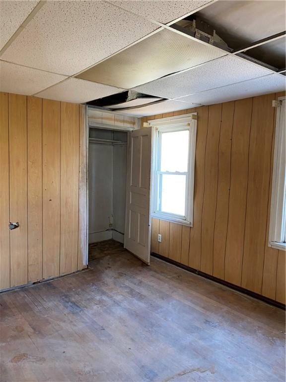 interior space featuring wood-type flooring, wood walls, a paneled ceiling, and a closet