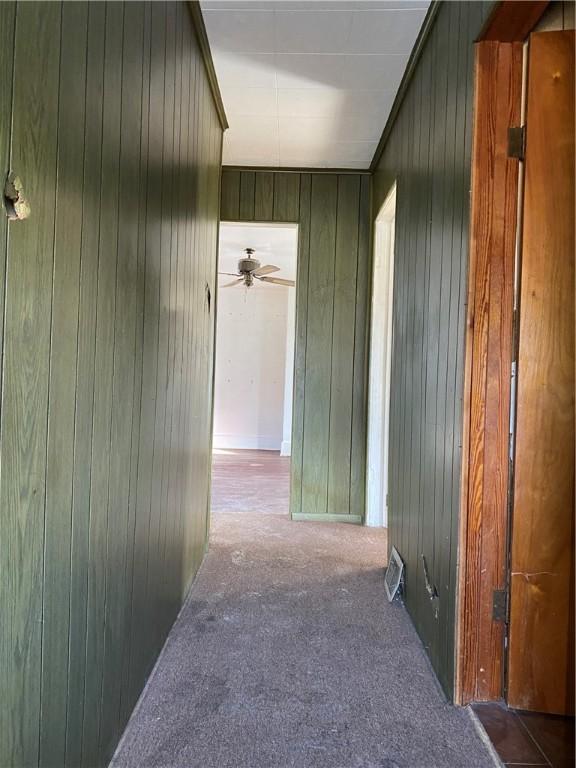 corridor with light carpet and wood walls