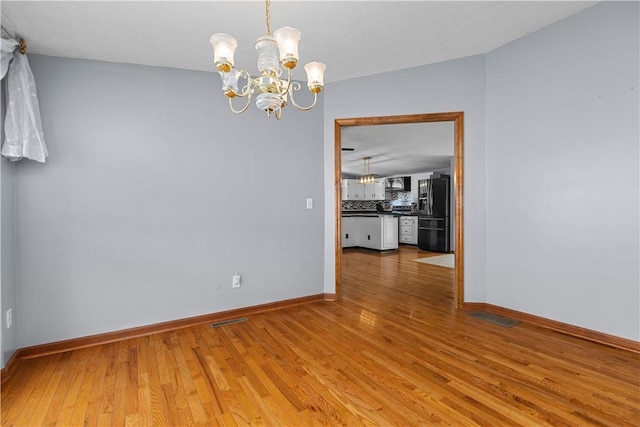 empty room featuring an inviting chandelier and hardwood / wood-style floors