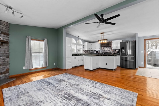 kitchen with vaulted ceiling with beams, white cabinets, backsplash, hanging light fixtures, and black fridge