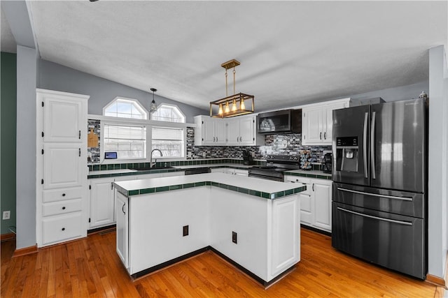 kitchen with lofted ceiling, a center island, refrigerator with ice dispenser, and stainless steel electric range