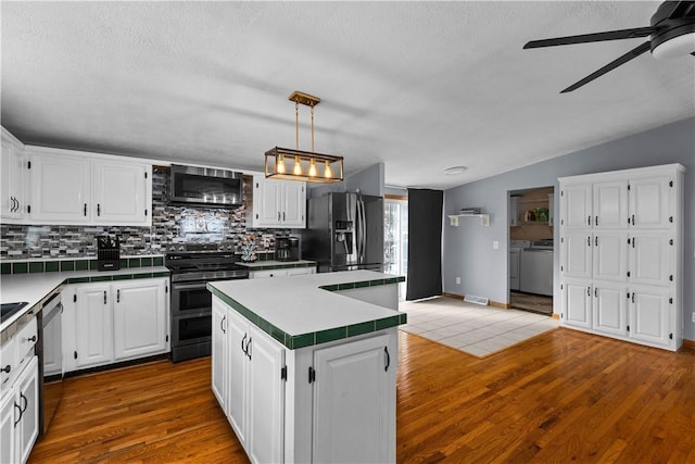 kitchen with a kitchen island, washer and dryer, white cabinets, backsplash, and stainless steel appliances