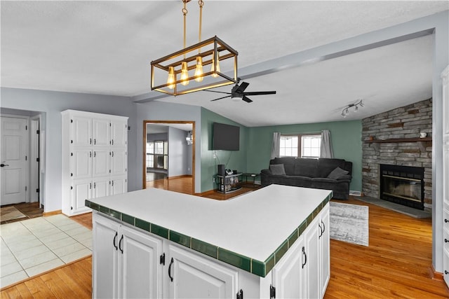 kitchen with a center island, vaulted ceiling with beams, white cabinets, and light hardwood / wood-style flooring