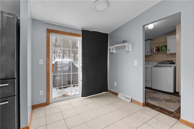 interior space featuring vaulted ceiling, independent washer and dryer, and light tile patterned flooring