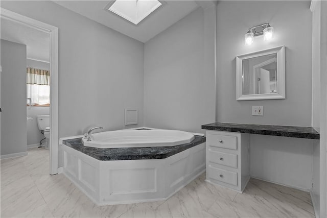 bathroom with vanity, toilet, a skylight, and a tub