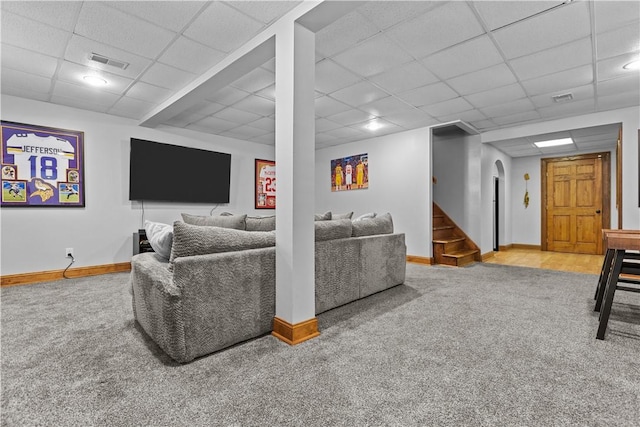 living room featuring carpet floors and a drop ceiling