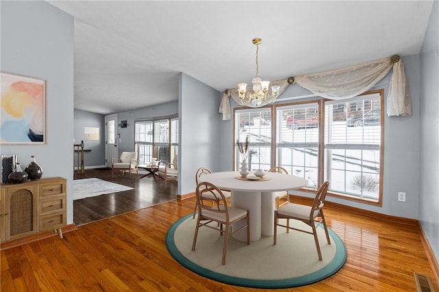 dining space with hardwood / wood-style floors and a notable chandelier