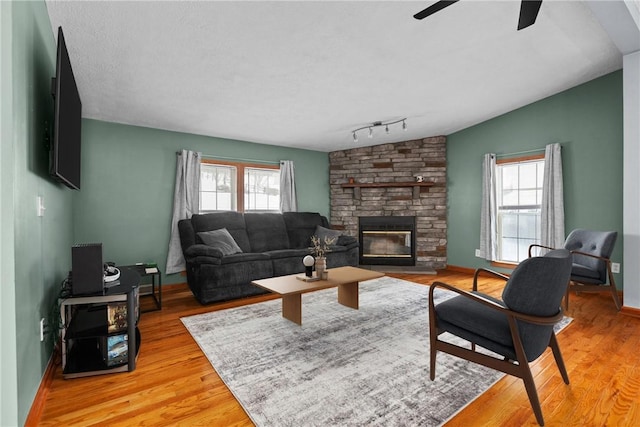 living room with track lighting, a healthy amount of sunlight, vaulted ceiling, and light hardwood / wood-style flooring