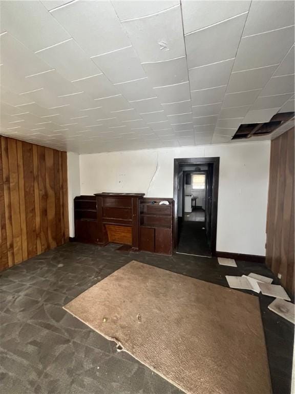 interior space featuring dark carpet and wooden walls