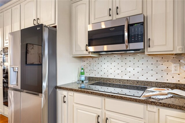 kitchen featuring black appliances, backsplash, and white cabinetry