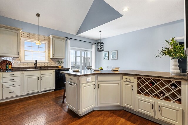 kitchen with dishwasher, decorative light fixtures, tasteful backsplash, sink, and cream cabinetry