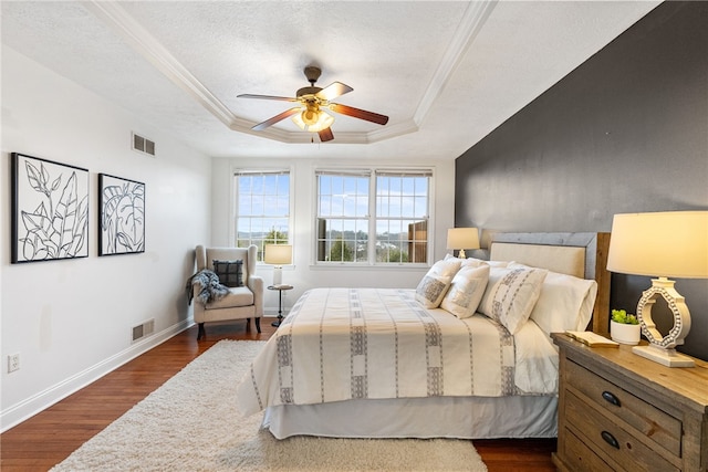 bedroom featuring crown molding, dark hardwood / wood-style flooring, a raised ceiling, and a textured ceiling