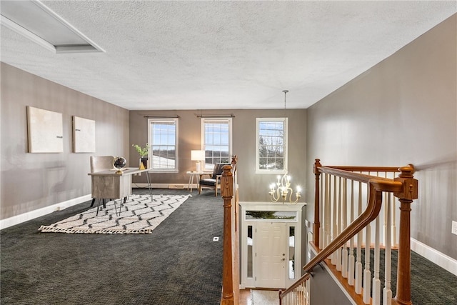 interior space with a chandelier, dark carpet, and a textured ceiling