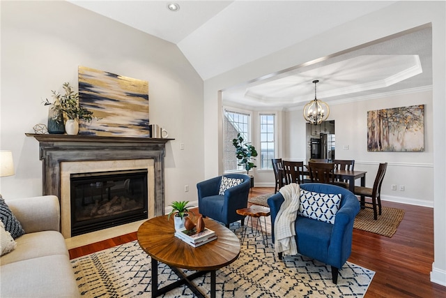 living room featuring a notable chandelier, a high end fireplace, wood-type flooring, and a raised ceiling