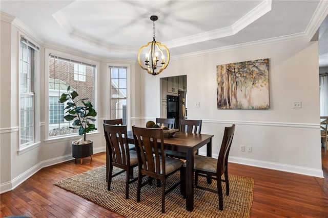 dining room with dark wood-type flooring, ornamental molding, a raised ceiling, and an inviting chandelier