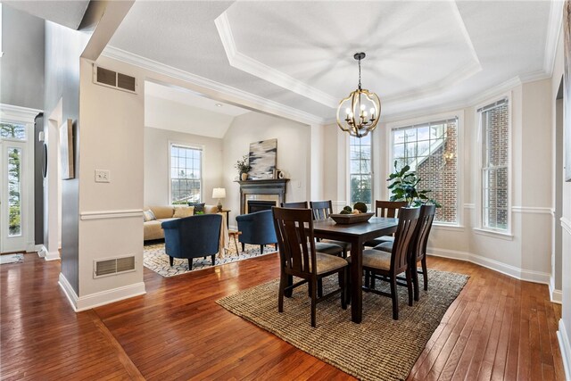 dining space with a healthy amount of sunlight, dark hardwood / wood-style floors, a notable chandelier, and ornamental molding