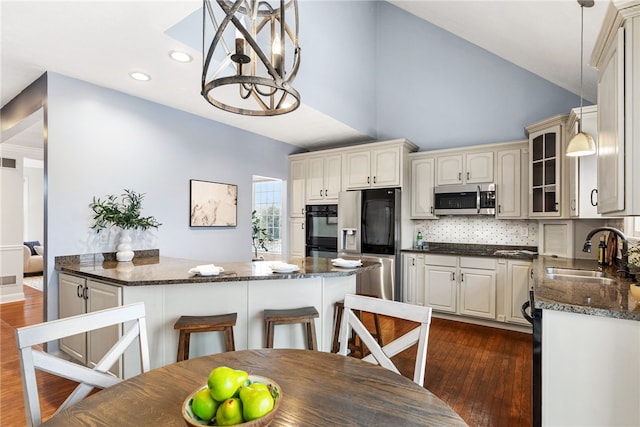 kitchen with appliances with stainless steel finishes, decorative light fixtures, tasteful backsplash, sink, and kitchen peninsula