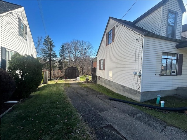 view of side of home with a storage shed and a lawn