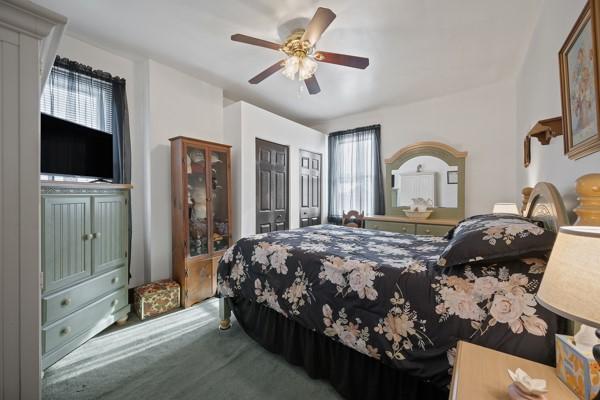 carpeted bedroom with multiple windows and ceiling fan