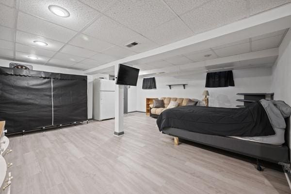 bedroom with white fridge, a paneled ceiling, and light hardwood / wood-style flooring