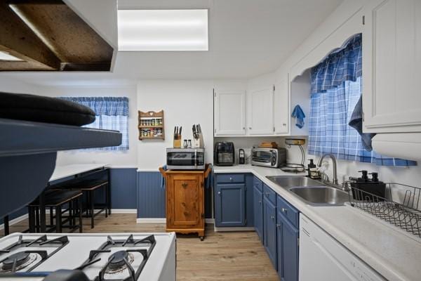 kitchen with sink, white appliances, light hardwood / wood-style flooring, blue cabinetry, and white cabinets