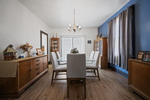 dining space with dark wood-type flooring and a chandelier