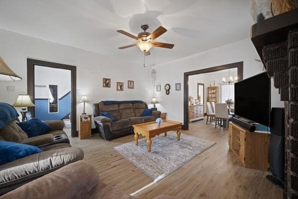 living room featuring ceiling fan with notable chandelier and light hardwood / wood-style flooring