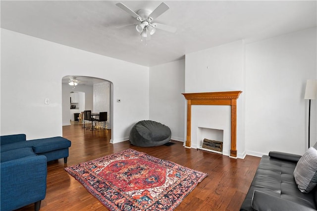 living room featuring dark wood-type flooring and ceiling fan