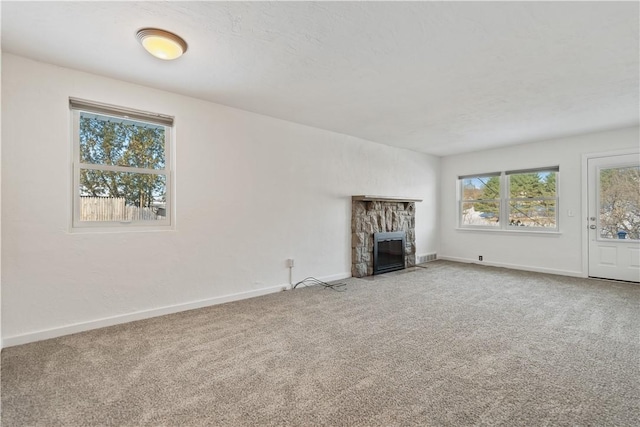 unfurnished living room with a stone fireplace and carpet floors