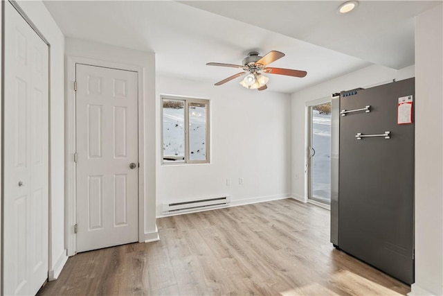 interior space with ceiling fan, a baseboard radiator, and light hardwood / wood-style floors