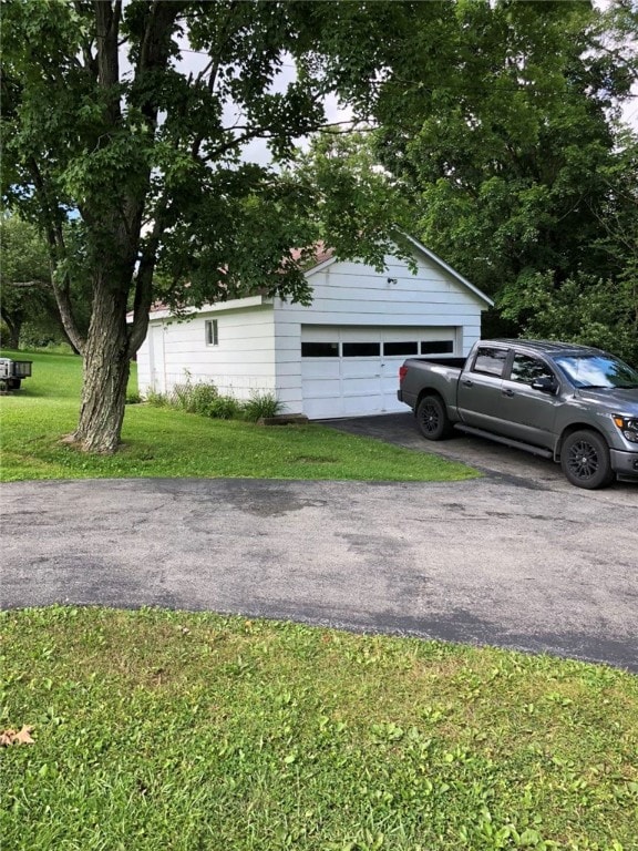 exterior space featuring a garage, a yard, and an outdoor structure