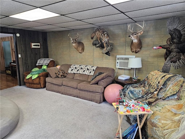 carpeted living room with a paneled ceiling and a wall mounted air conditioner