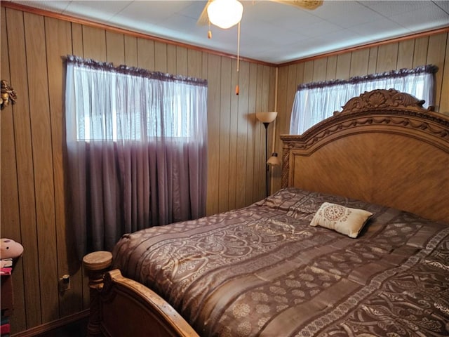 bedroom featuring ceiling fan and wood walls