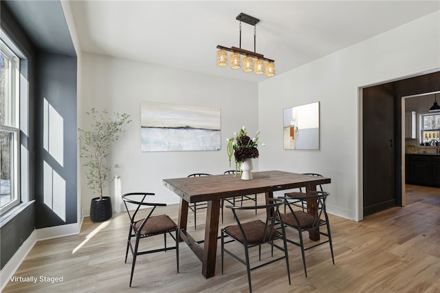 dining area featuring baseboards, light wood finished floors, and plenty of natural light