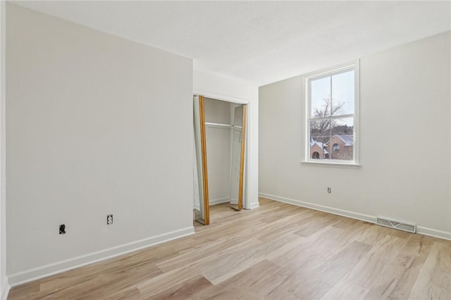 unfurnished bedroom with light wood-style floors, a closet, baseboards, and visible vents