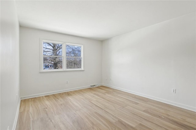spare room featuring light wood-type flooring, baseboards, and visible vents